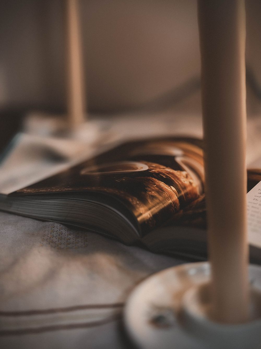A lit candle beside an open book, evoking a calming evening reading ritual.