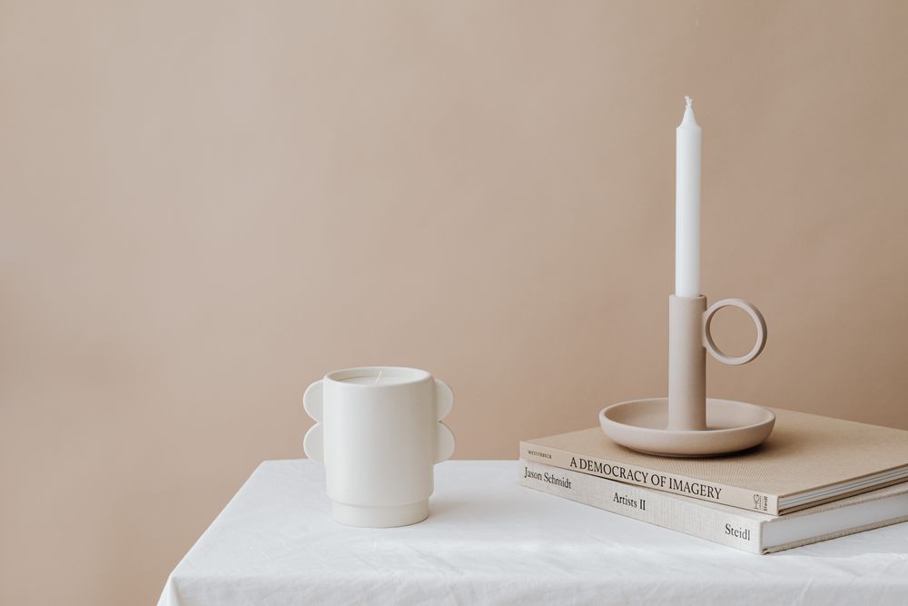 Neutral-toned candles in glass jars on a flat surface.